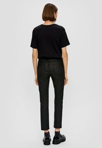 Czarna bawełniana koszulka z krótkimi rękawami zestawiona z czarnymi, dopasowanymi spodniami. Ubranie uzupełniają masywne czarne buty o gładkiej fakturze.