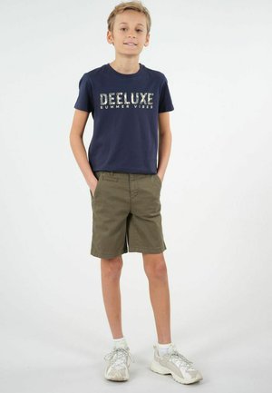 T-shirt à manches courtes marine avec un graphique "DELUXE SUMMER VIBES", associé à un short vert olive. Baskets blanches avec accents gris.