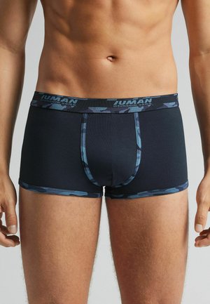 Marineblaue Shorts mit einem gemusterten blauen Bund. Weicher, dehnbarer Stoff mit einer passgenauen Form und einem unterstützenden Beutel.