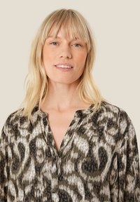 Blouse s potiskem zvířecího vzoru v zelených a béžových odstínech, s výstřihem do V, dlouhými rukávy a měkkou texturovanou tkaninou.