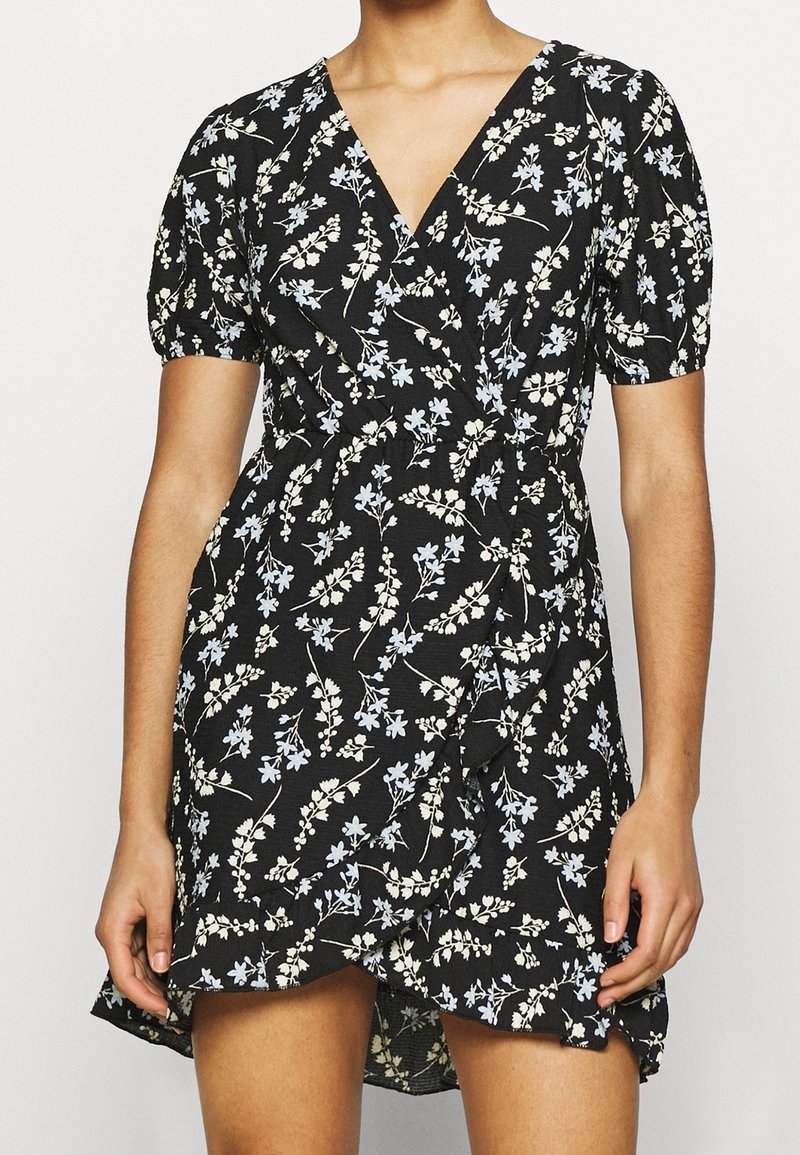 Černé zavinovací šaty s krátkými balónovými rukávy, s květinovým vzorem v světle modré a krémové barvě, a volánkovým lemem. Vyrobeno z lehkého materiálu.