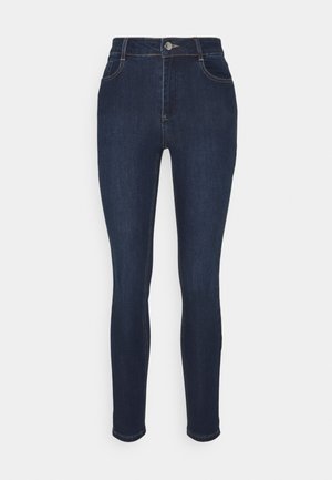 Jean skinny bleu foncé en denim, à taille haute, avec un design à cinq poches et de subtils détails de surpiqûres jaunes.