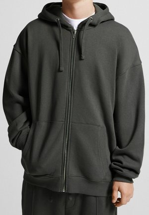 Sudadera con cremallera de color gris oscuro hecha de un suave tejido de algodón. Presenta una capucha, bolsillos frontales y puños acanalados en las mangas y el dobladillo.