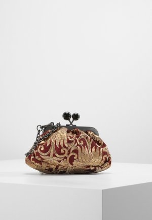 Kleine Vintage-Börse mit Metallverschluss, rotem Stoff und aufwändiger goldener Blumenstickerei, die auf einem weißen Sockel vor einem schlichten Hintergrund liegt.