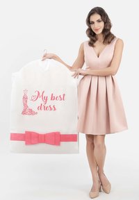 White garment bag with a pink bow and the text "My best dress," featuring a dress illustration. Model in a light pink dress.