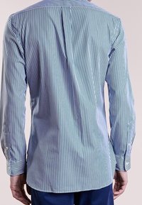 Långärmad skjorta i ljusblå och vita vertikala ränder, med rundad nederkant, knäppta manschetter och mjukt bomullstyg.