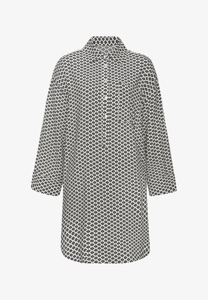 Tunika s uzorkom u crno-bijeloj boji s kragnom, dugim rukavima i gumbima sprijeda. Ima geometrijske oblike i opušteni kroj.