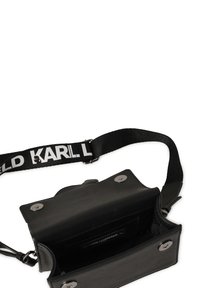 Borsa in pelle nera con forma piatta, hardware in metallo argentato e una tracolla nera regolabile con branding bianco "KARL LAGERFELD". Interno aperto visibile.