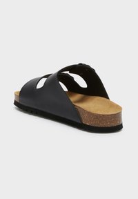 Sandalo scivoloso in pelle nera con design a fori, soletta in sughero e suola testurizzata. Rivestimento interno in morbido camoscio per il comfort. Forma arrotondata.
