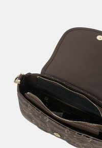 Bruin leren handtas met een gestructureerd exterieur, ritssluitingen en een gouden drukknoopsluiting. Het interieur heeft meerdere vakken voor organisatie.