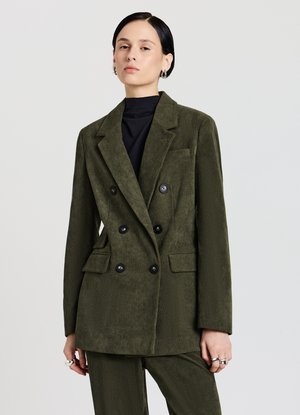 Double-breasted corduroy blazer in olive green, featuring black buttons, notched lapels, and front pockets. Smooth texture with vertical ribs.