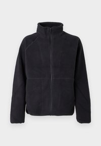 Giacca in pile nera con zip, maniche lunghe e colletto alto, realizzata in un morbido tessuto testurizzato, mostrata su uno sfondo bianco semplice.