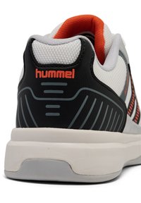 Hvide og sorte sportsko med en struktureret overdel, orange detaljer og en tyk cremefarvet sål med detaljeret dækdesign.