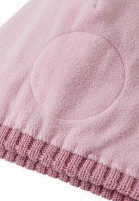 Jasnoróżowa tkanina polarowa z okrągłą łatą i teksturowanymi mankietami w dopasowanym odcieniu różu. Miękka tekstura i gładkie wykończenie to wyróżniające cechy.