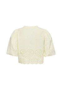 Blouse crème à manches courtes avec manches bouffantes, ourlet festonné et broderie ajourée en forme de cœur le long du bas.
