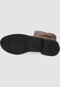 Stivale alla caviglia in pelle marrone con suola in gomma nera texture, dotato di punta arrotondata e sottili dettagli di cucitura lungo i lati.