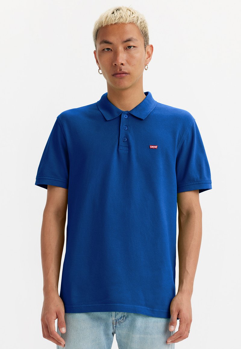 Polo azul feito de algodão, com colarinho e três botões, apresentando um pequeno logo vermelho da Levi's no lado esquerdo do peito.