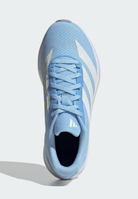 Chaussure de sport bleu clair en mesh, avec des rayures blanches, un bout arrondi et des lacets plats, surface texturée sur le dessus.