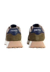 Le sneakers in suede verde presentano una suola intermedia bianca e beige, con dettagli blu navy sul tallone etichettati "TEDDY" e "SMITH."