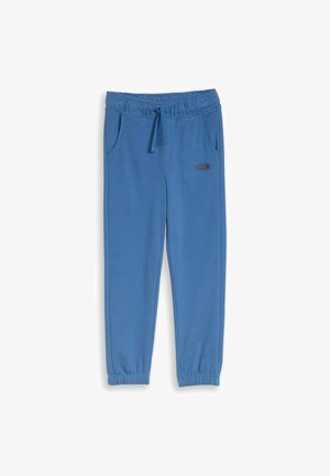 Pantalones jogger azules con cintura elástica, cordón, bolsillos laterales, tobillos con puños y un pequeño logotipo "NYC" en el muslo izquierdo.