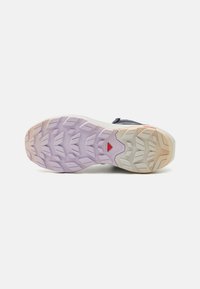 Løpesko såle med et teksturert design, med en lys lilla-til-beige gradient. Mønsteret på sålen inkluderer dype spor for grep.