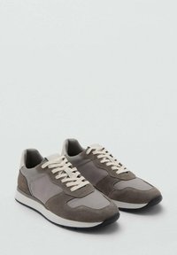Scarpe da ginnastica atletiche grigie con pannelli in suede e mesh, lacci bianchi, suola in gomma e design con punta arrotondata. Stile minimalista e casual.