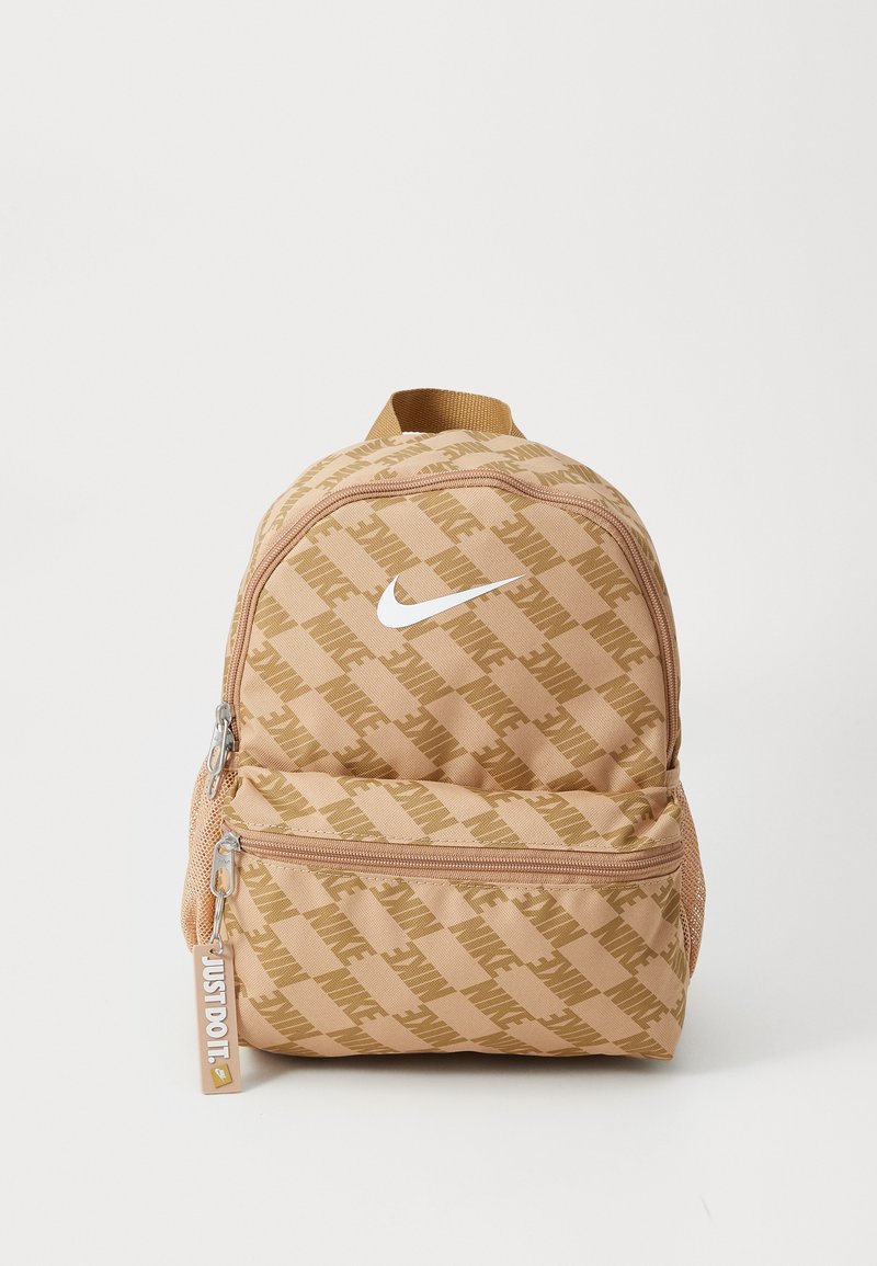 Beige Nike ryggsekk med lys brun diagonalt logo mønster, som har et hvitt swoosh, to glidelåslommer og et bærehåndtak på toppen.