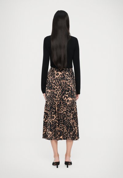 Sort langærmet top parret med en beige leopardmønstret midi-nederdel med tiered design og en glat tekstur. Sorte hæle.