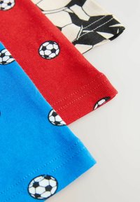 Tre bomulls t-shirts: en blå med fotbollar, en röd med fotbollar och en svart-vit randig design. Alla har en slät textur.