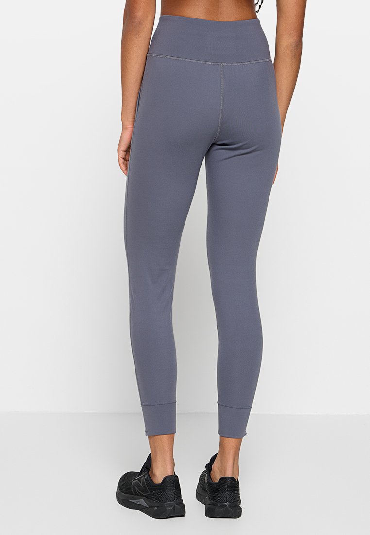 Legging de sport gris avec une taille haute, design ajusté et chevilles resserrées ; fabriqué dans un matériau lisse et extensible.
