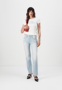White short-sleeve t-shirt with a subtle graphic, light blue high-waisted jeans, black high-heeled shoes, and a red faux leather bag.