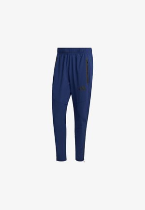 Navy athletic pants with an elastic waistband, side zip pockets, tapered legs, and black branding accents on the lower front.