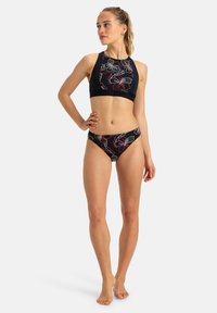 Conjunto de bikini negro con top corto de cuello alto y parte inferior de cintura baja, con colorido bordado floral. Tejido suave, diseño ajustado.