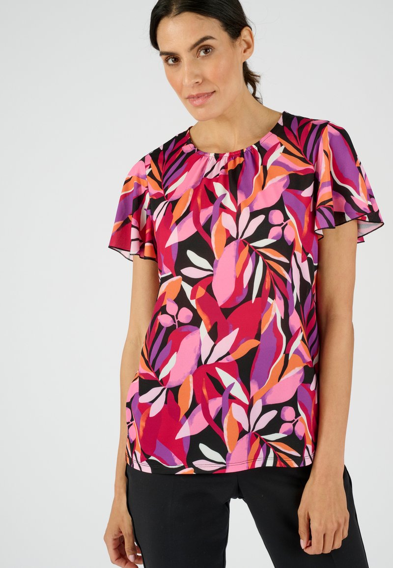 Blusa de manga corta en tela ligera con fondo negro y vibrantes patrones de hojas en rosa, naranja y púrpura. Detalle de escote con volantes.