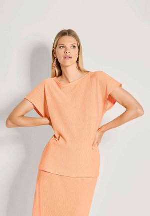 Pfirsichfarbener zweiteiliger Anzug mit locker sitzendem Oberteil mit kurzen Ärmeln und knielangem Rock, strukturiertes Gewebe mit dezenten Streifen.