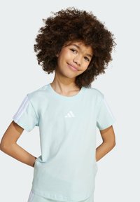 Light blue cotton t-shirt with short sleeves, featuring three white stripes on each shoulder and a small white logo on the chest.