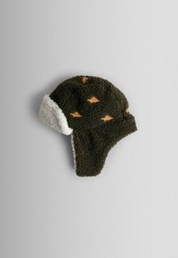 Cappello in pile marrone con rivestimento bianco, dotato di motivi di dinosauri arancioni che sbucano. Pannelli per le orecchie estesi per una maggiore calore.