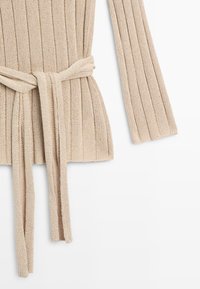 Beige ribbed knit cardigan with a matching belt tied at the waist, shown with one long sleeve on a white background.