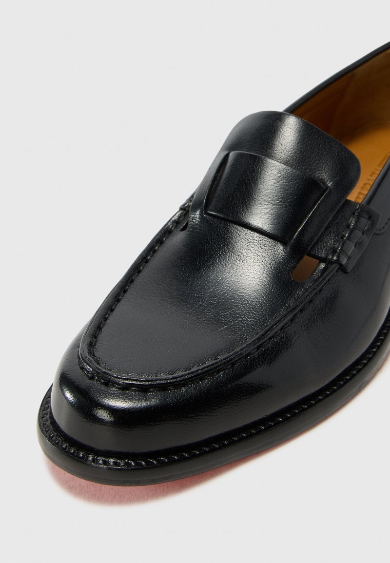 Czarny skórzany loafers z gładkim wykończeniem, z ozdobnym paskiem i przeszyciem wokół krawędzi. Niskoprofilowy design z okrągłym noskiem.