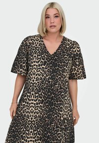 Haljina s uzorkom leoparda, V-izrezom, kratkim rukavima i do koljena dugom rubom. Izrađena od glatkog materijala; sadrži hrabar crno-bijeli uzorak.