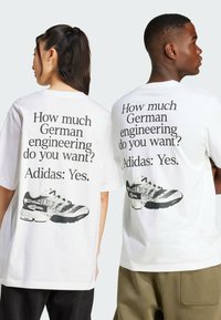 Vit t-shirt med stor svart text på baksidan: "Hur mycket tysk ingenjörskonst vill du ha? Adidas: Ja." Grafik av en sneaker under texten.