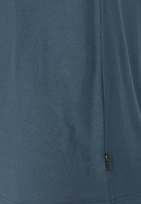 Dark blue athletic shirt with a smooth texture, short sleeves, and a side label. Features a relaxed fit and simple design.