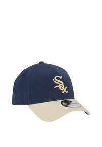 Marineblaue Mütze mit beigem Schirm, versehen mit einem bestickten weißen "Sox"-Logo. Hergestellt aus Stoff mit glatter Textur und abgerundetem Kronendesign.