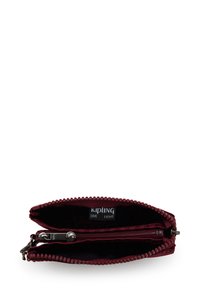 Bordeaux-färgad plånbok med dragkedja, med strukturerat yttre, två fack och en Kipling-logotag inuti. Har en mönstrad dragkedjepull.