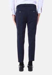 Pantaloni da abito blu navy con una vestibilità su misura, frontale liscio, due tasche posteriori con bottoni e dettagli di piega lungo le gambe.