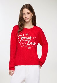 Czerwona sweter dzianinowy z wzorem w warkocze, z białym haftowanym napisem "Czas Świąt", akcentami w kształcie serc i płatków śniegu. Długie rękawy, okrągły dekolt.