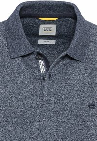 Czarny polos z organicznej bawełny. Posiada teksturowany materiał, klasyczny kołnierzyk oraz zapięcie na trzy guziki. Logo na klatce piersiowej.