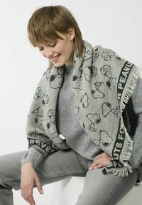 Grijze geweven sjaal met een overal Snoopy-patroon, met zwarte accenten en franjes. Zachte textuur, geschikt voor casual kleding.
