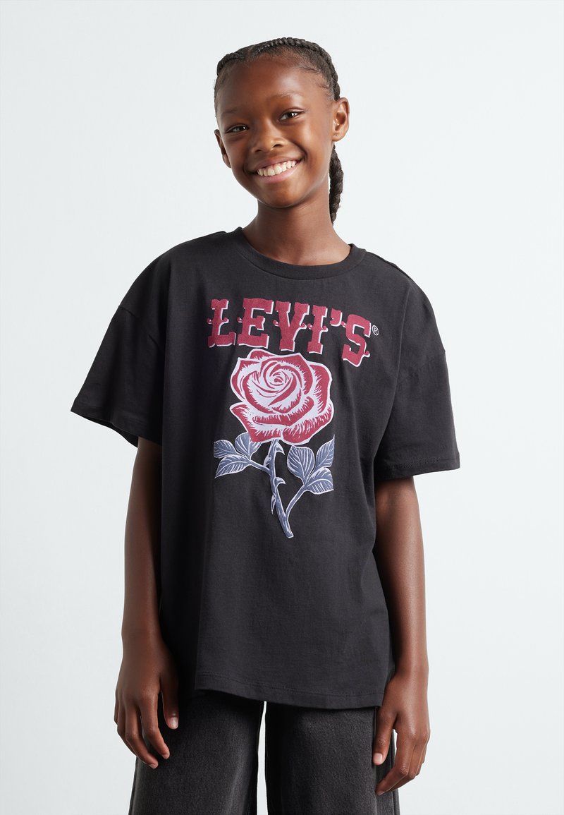 Camiseta de algodón negra con un gran gráfico de una rosa blanca y roja con el texto "LEVI'S" arriba. Corte relajado y mangas cortas, textura suave.