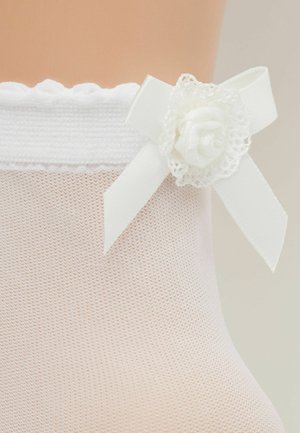 Collant bianchi con pizzo in cima realizzati in un tessuto trasparente e testurizzato. Presentano un piccolo fiore in tessuto e un nastro decorativo sul lato.
